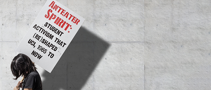 protester holding "Anteater Spirit" sign in front of a grey wall