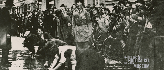 USHMM Some Were Neighbors traveling exhibit photo showing Germans and Nazi soliders standing over Jews in the street in Nazi Germany